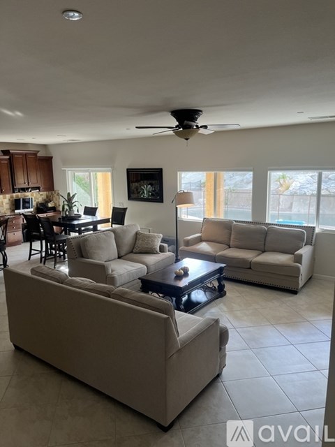A living room with a large couch and a ceiling fan.