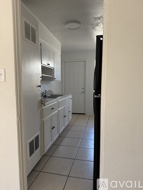 A kitchen with white cabinets and a black refrigerator.