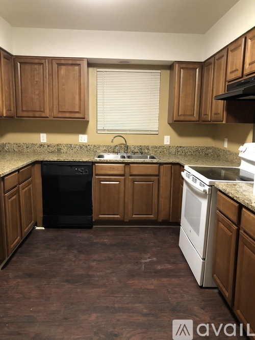 A kitchen with brown cabinets and a black dishwasher.