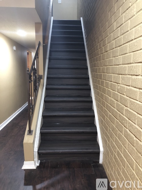 A staircase with a metal railing and a brick wall on one side.