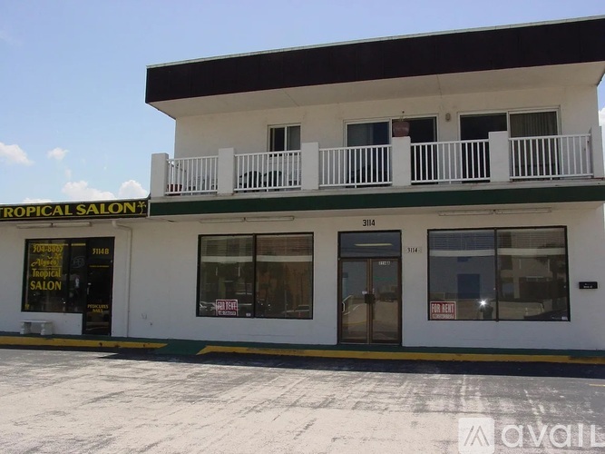 A white building with a balcony and a sign that says "Tropical Salon".