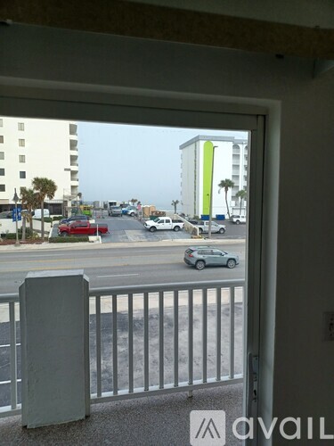 A view from a balcony looking out at a street with cars and buildings.