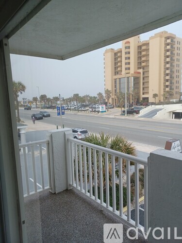 A view from a balcony overlooking a busy street with cars and buildings.