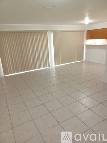 A room with white tiled flooring and a window with blinds.