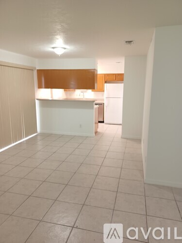 A kitchen area with a white refrigerator and a countertop with a brown backsplash.