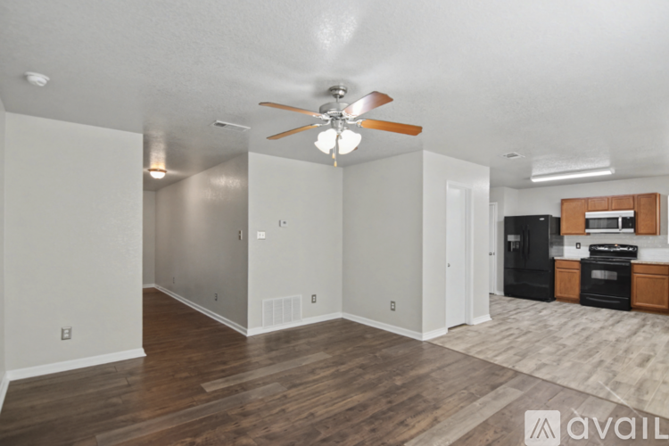 A spacious living room with a ceiling fan and hardwood floors.