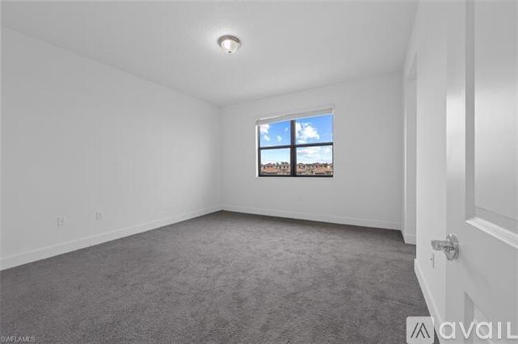 A room with a carpeted floor and a window showing a view of a building and the sky.
