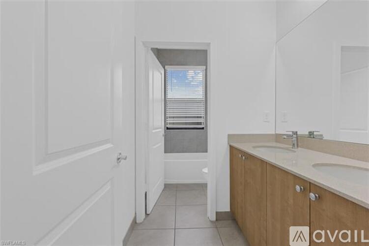 A bathroom with a sink, mirror, and a window with blinds.