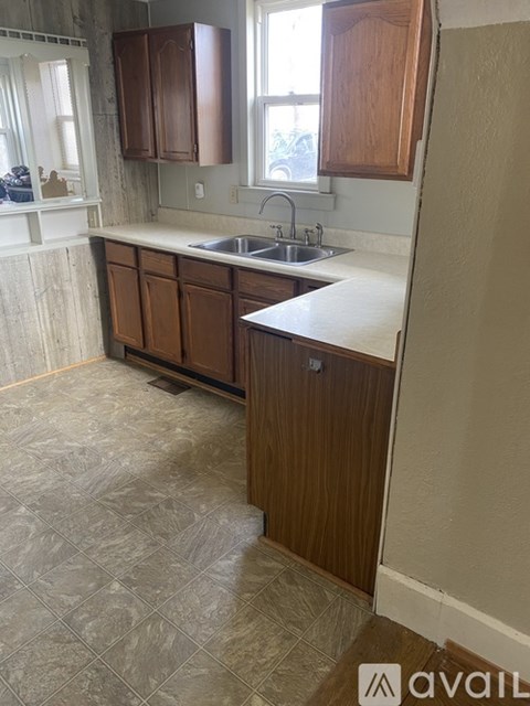 A kitchen with wooden cabinets and a tiled floor.