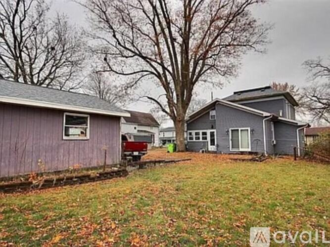 A house with a grey roof and a red truck in front of it.