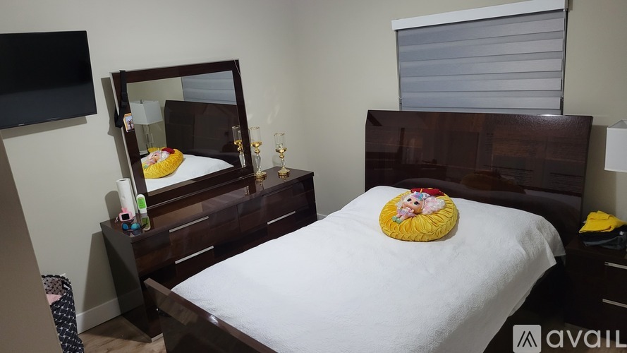 A bedroom with a bed, a mirror, and a TV.