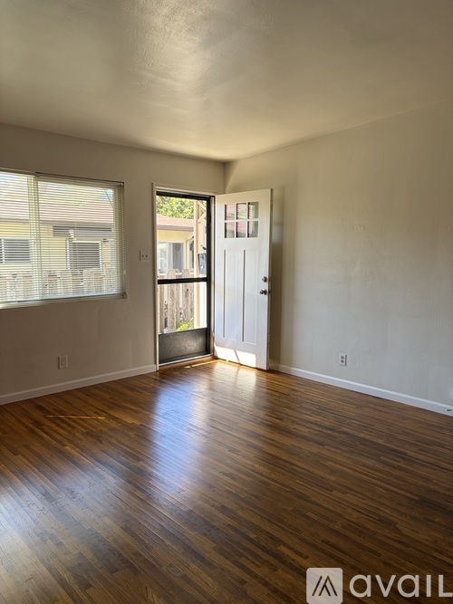A room with wooden floors and a door leading to a balcony.