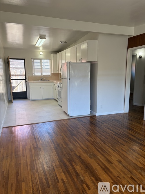 A kitchen with white appliances and wooden floors.
