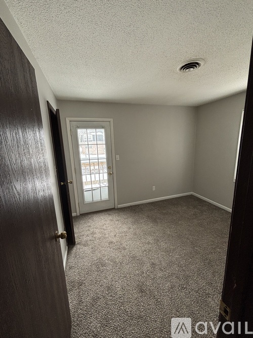 A room with a carpeted floor and a door leading to a balcony.