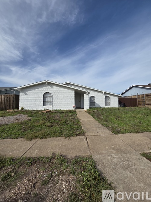 A white house with a grey roof and a brown fence.