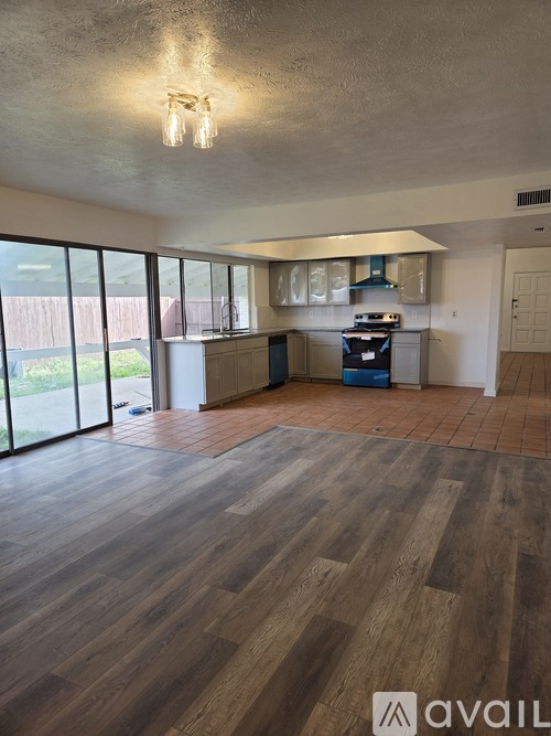 A spacious room with wooden flooring and a large window.
