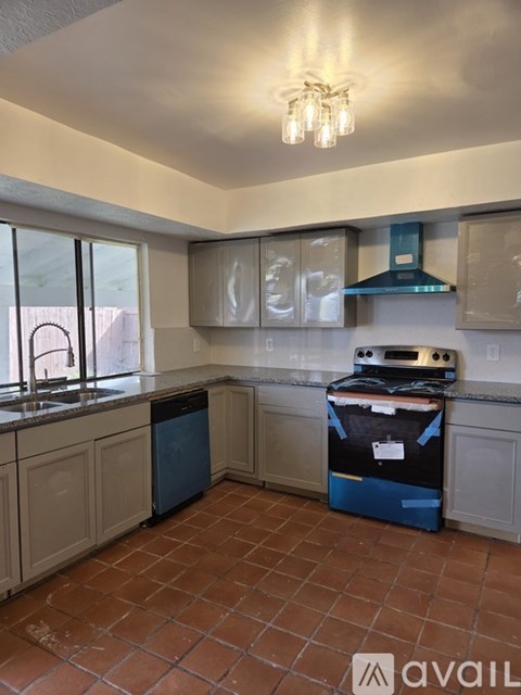 A kitchen with a blue dishwasher and a black oven.