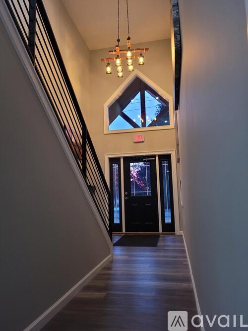 A hallway with a chandelier and a window with a view of the night sky.