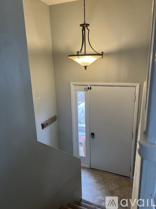 A hallway with a white door and a hanging light fixture.