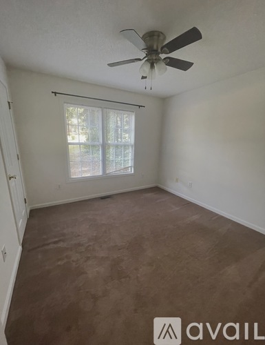 A room with a ceiling fan and a window with blinds.