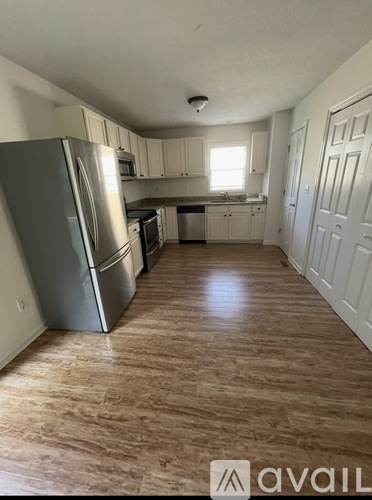 A kitchen with a refrigerator, microwave, oven, and sink.
