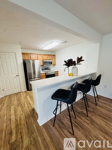 A kitchen with a white counter and black chairs.