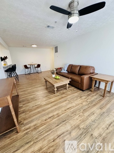 A living room with a brown couch and a ceiling fan.