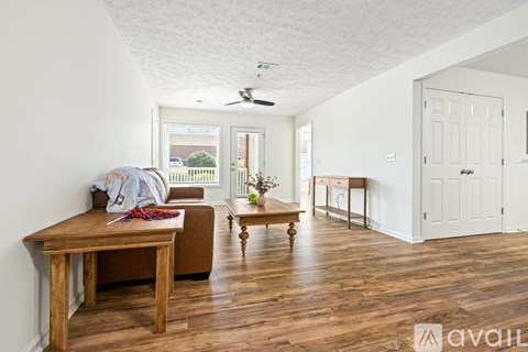 A living room with a brown couch and a ceiling fan.