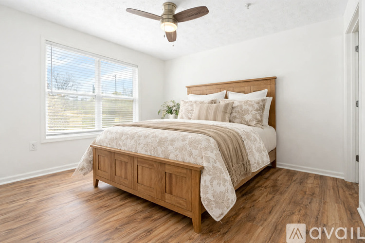 A bedroom with a bed, a bench, and a ceiling fan.