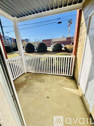 A patio with a white railing and a view of a building in the distance.