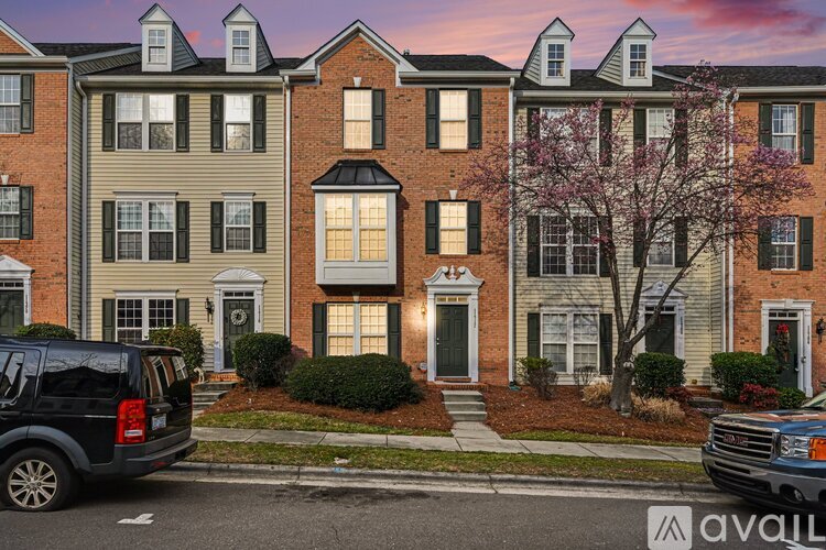 A row of townhouses with a black SUV and a blue truck parked in front.