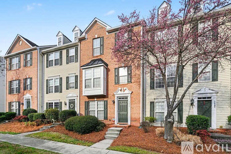 A row of townhouses with front yards and flowering trees.