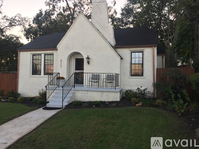 A white house with a black roof and a black metal railing on the front porch.