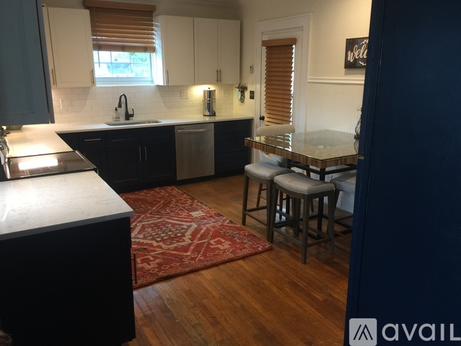 A kitchen with dark wood floors and a red rug.