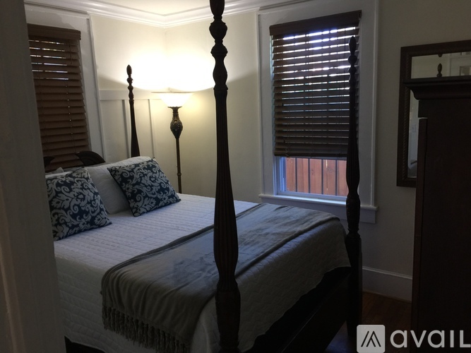 A bedroom with a four poster bed and a window with blinds.