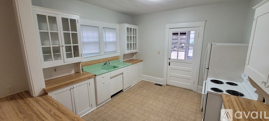 A kitchen with white cabinets and a green countertop.