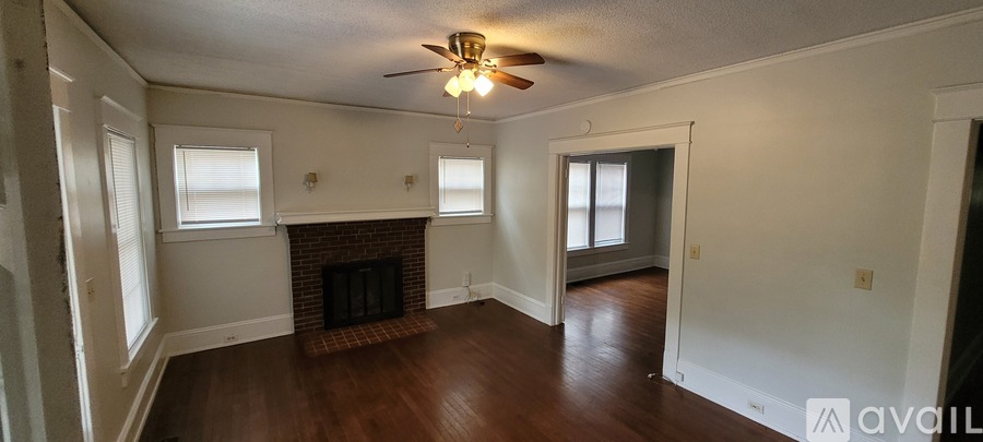A living room with a fireplace and a ceiling fan.
