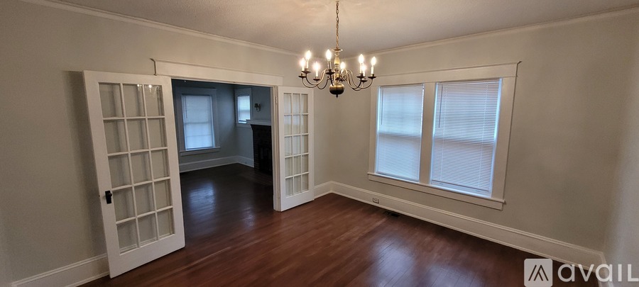 A room with a chandelier and a window with blinds.