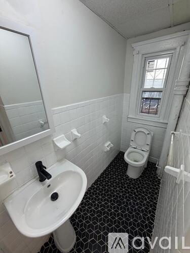A bathroom with a white sink, toilet, and black and white tiled floor.