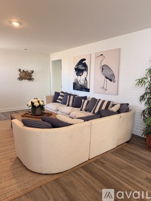 A living room with a white couch and a painting of a bird on the wall.