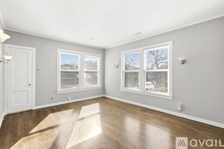 A room with wooden floors and two windows.