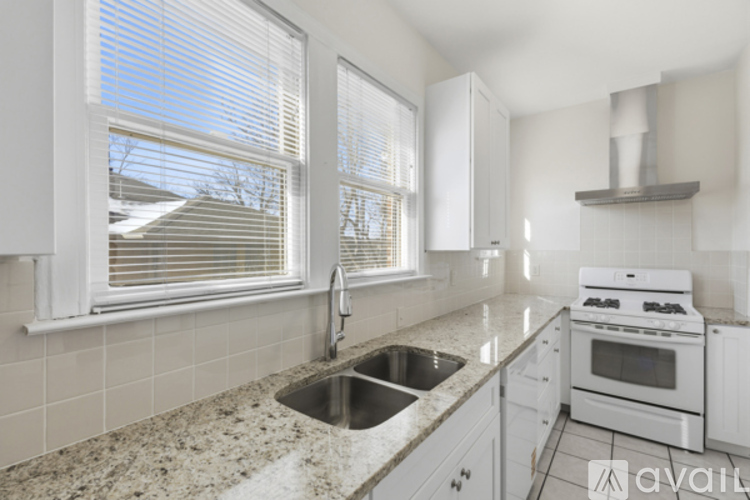 A kitchen with white cabinets and a granite countertop.