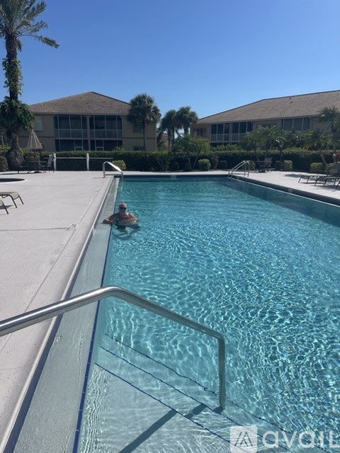 A man is swimming in a pool with a metal railing.