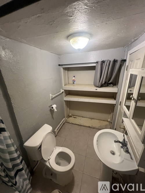 A bathroom with a toilet, sink, and a small shelf.