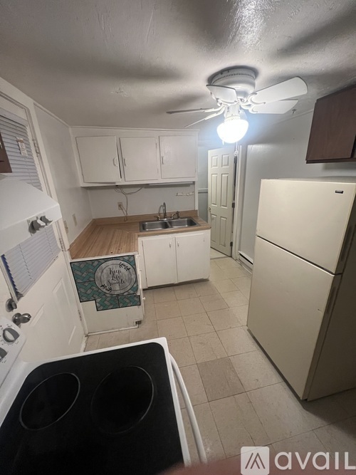 A kitchen with white appliances and a fan on the ceiling.
