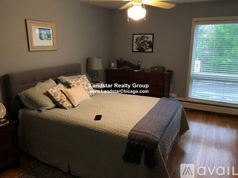 A bedroom with a bed, nightstand, lamp, and window.