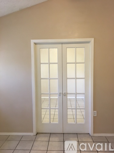 A white double door with glass panels is set in a beige wall.