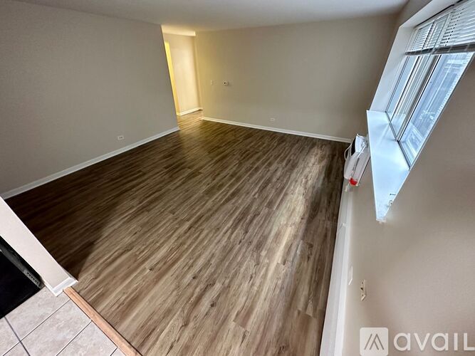 A room with wooden flooring and a window on the right side.