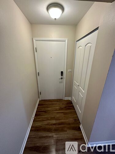 A hallway with a white door and wooden floor.