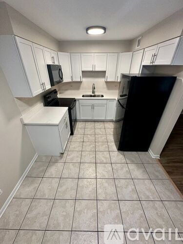 A kitchen with white cabinets and black appliances.